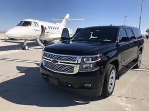 a black suv parked next to a white airplane at JAXEX